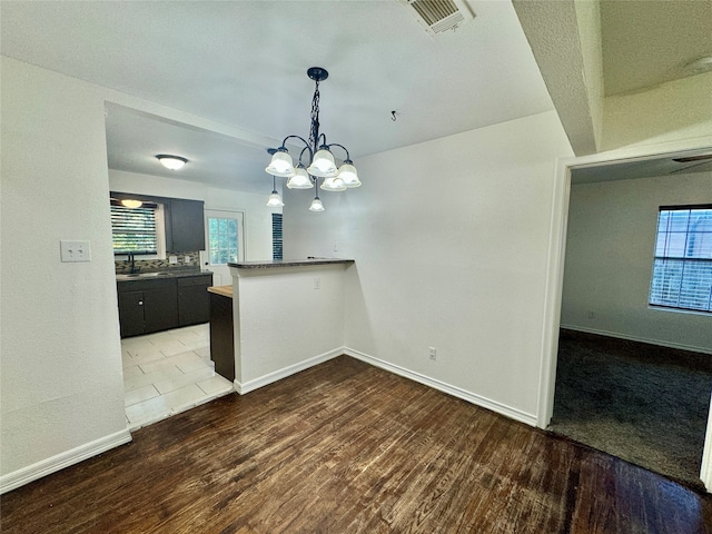 unfurnished room with wood-type flooring, a notable chandelier, and sink