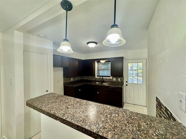 kitchen with pendant lighting, sink, kitchen peninsula, and decorative backsplash