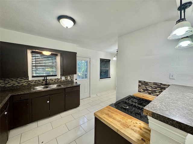 kitchen featuring decorative backsplash, light tile patterned flooring, dark brown cabinets, decorative light fixtures, and sink