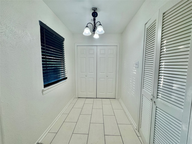 corridor with a chandelier and light tile patterned floors