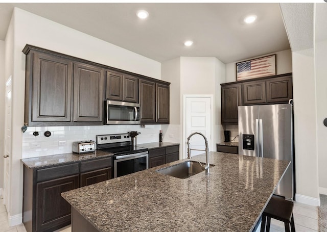 kitchen with a breakfast bar, tasteful backsplash, sink, an island with sink, and stainless steel appliances