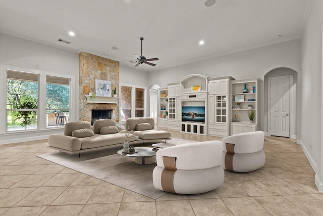 living room with a stone fireplace, crown molding, light tile patterned floors, and ceiling fan