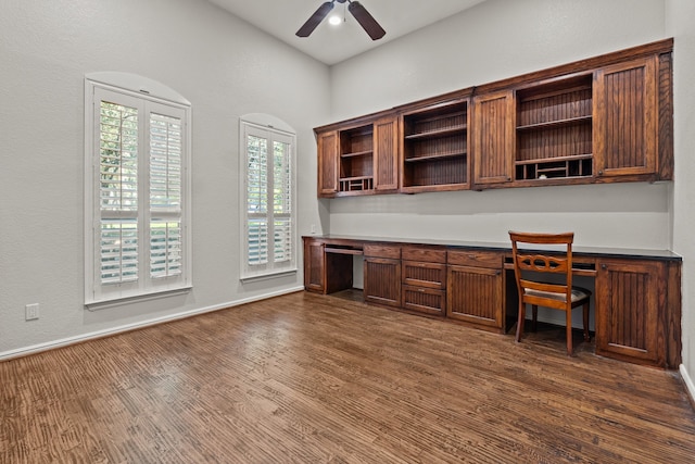 unfurnished office with dark hardwood / wood-style floors, ceiling fan, and built in desk