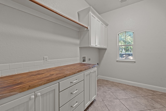 laundry area featuring hookup for an electric dryer, cabinets, light tile patterned floors, and hookup for a washing machine