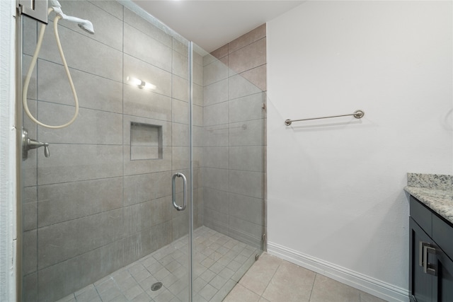 bathroom featuring tile patterned floors, a shower with door, and vanity