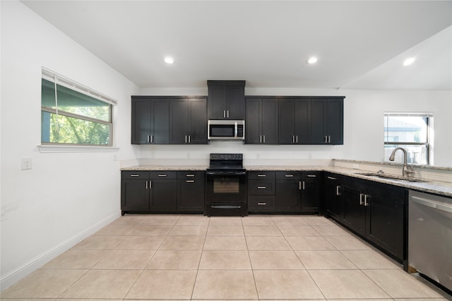 kitchen featuring light stone counters, light tile patterned floors, appliances with stainless steel finishes, and sink