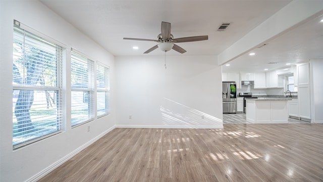 unfurnished living room featuring ceiling fan, light hardwood / wood-style flooring, and sink