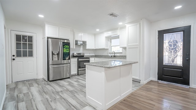 kitchen featuring light hardwood / wood-style flooring, stainless steel appliances, white cabinetry, and light stone counters