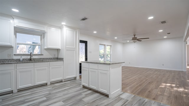 kitchen with ceiling fan, white cabinets, and light stone counters