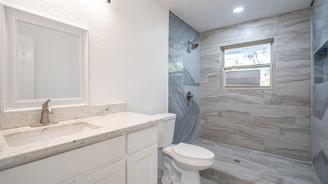 bathroom featuring tiled shower, vanity, and toilet