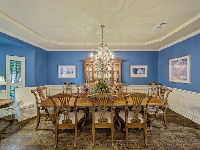 dining space featuring an inviting chandelier, a raised ceiling, and ornamental molding