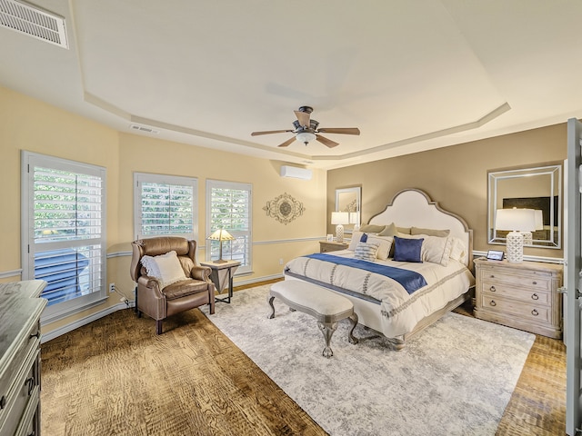 bedroom with ceiling fan, a raised ceiling, and hardwood / wood-style floors