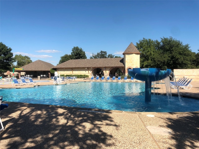 view of pool featuring a water slide, pool water feature, and a patio area