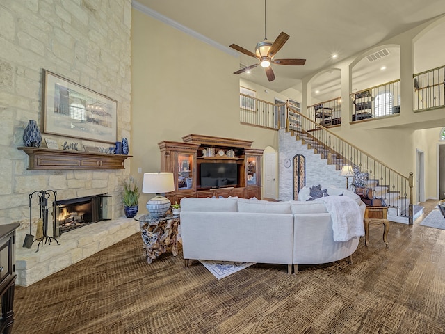 living room with ornamental molding, a high ceiling, a fireplace, and ceiling fan