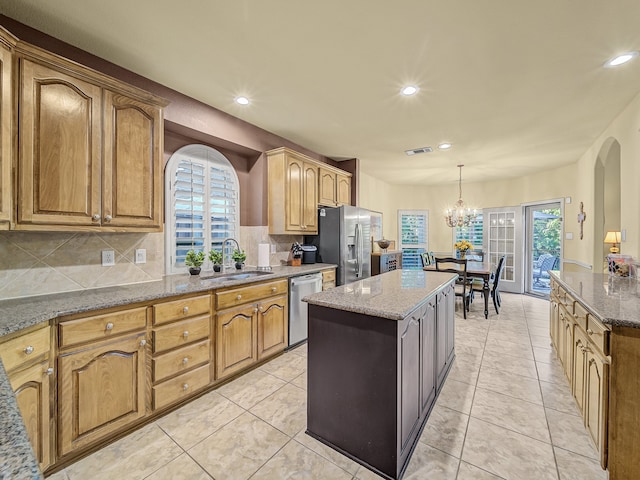 kitchen with appliances with stainless steel finishes, light stone countertops, a center island, and a wealth of natural light