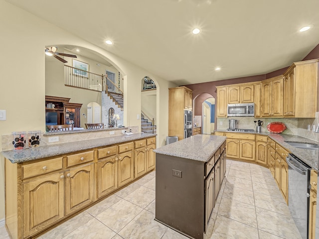 kitchen featuring ceiling fan, sink, kitchen peninsula, a kitchen island, and appliances with stainless steel finishes