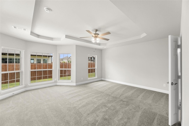 unfurnished room with carpet floors, a tray ceiling, and ceiling fan