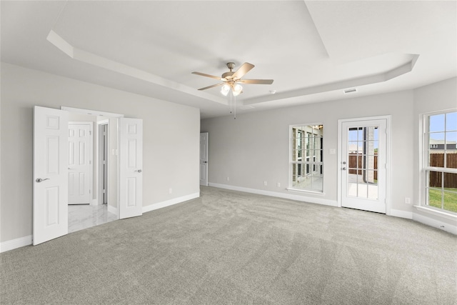 unfurnished room with light colored carpet, ceiling fan, and a raised ceiling