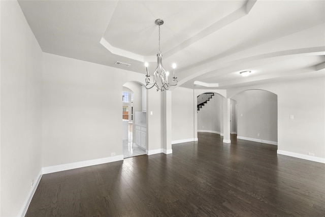 unfurnished room with a chandelier, a tray ceiling, and dark hardwood / wood-style floors