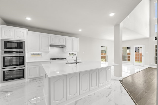 kitchen featuring sink, a center island with sink, white cabinetry, appliances with stainless steel finishes, and light hardwood / wood-style floors