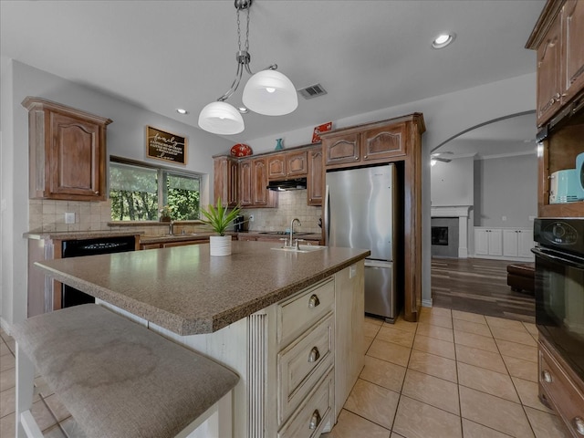 kitchen featuring an island with sink, light tile patterned floors, stainless steel appliances, a kitchen bar, and sink