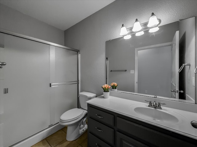 bathroom featuring vanity, a shower with shower door, toilet, and tile patterned floors