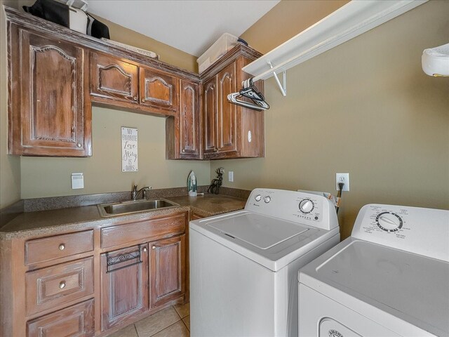 laundry room with washer and clothes dryer, light tile patterned floors, cabinets, and sink