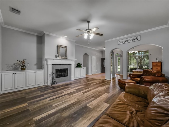 living room with ornamental molding, dark wood-type flooring, and ceiling fan