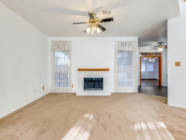 unfurnished living room with a brick fireplace, carpet, and ceiling fan