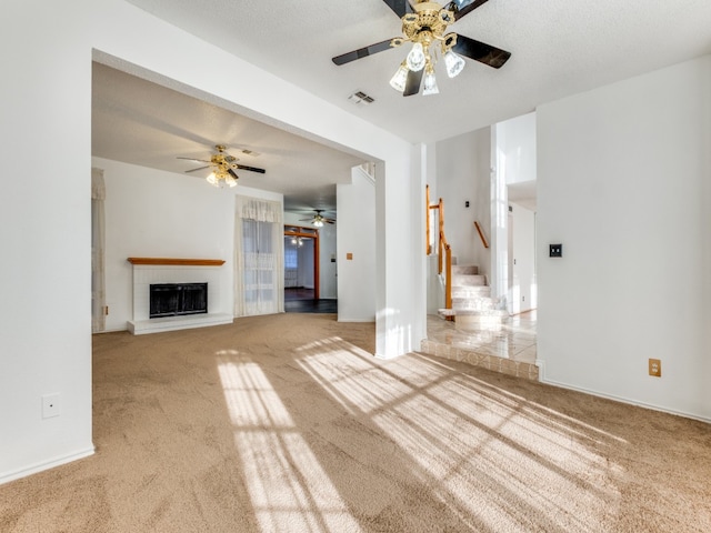 unfurnished living room featuring ceiling fan, a textured ceiling, a brick fireplace, and carpet flooring