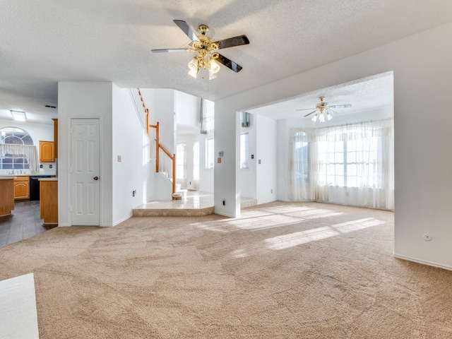 unfurnished living room featuring a textured ceiling, ceiling fan, and light colored carpet