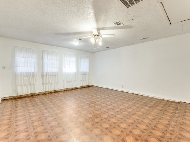 spare room with a textured ceiling, light parquet flooring, and ceiling fan