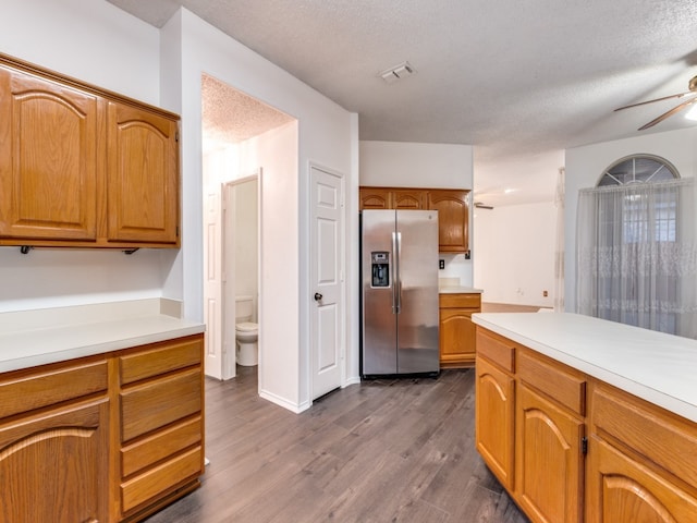 kitchen featuring a textured ceiling, ceiling fan, stainless steel fridge with ice dispenser, and dark wood-type flooring