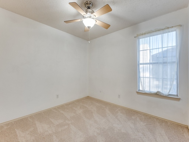 spare room featuring a textured ceiling, light carpet, and ceiling fan