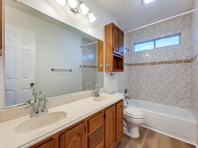 full bathroom featuring wood-type flooring, a textured ceiling, tiled shower / bath combo, vanity, and toilet