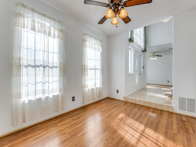 empty room with ceiling fan, a textured ceiling, and light hardwood / wood-style flooring