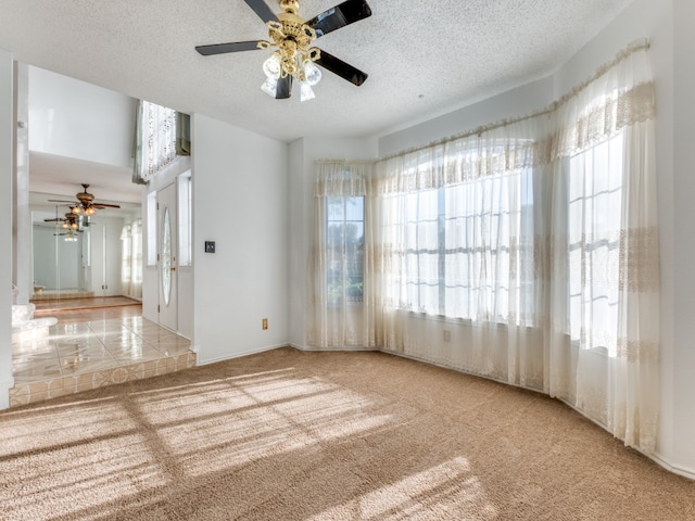 carpeted empty room with ceiling fan and a textured ceiling