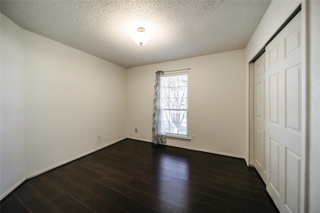 unfurnished bedroom featuring a textured ceiling, dark wood-type flooring, and a closet