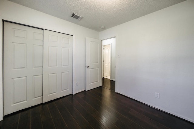 unfurnished bedroom featuring a textured ceiling, dark hardwood / wood-style floors, and a closet