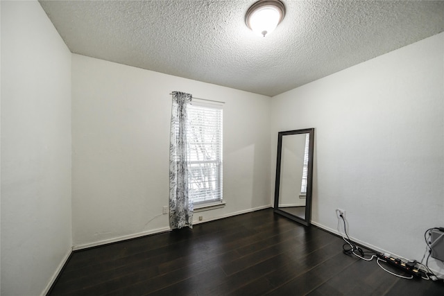 empty room with a textured ceiling and dark hardwood / wood-style flooring