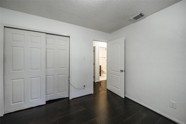 unfurnished bedroom featuring a closet, dark wood-type flooring, and a textured ceiling