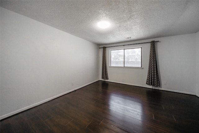 empty room featuring a textured ceiling and dark hardwood / wood-style floors