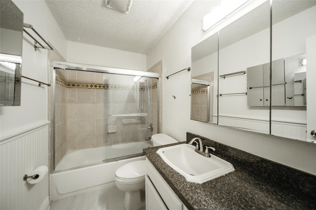 full bathroom with a textured ceiling, shower / bath combination with glass door, vanity, and toilet