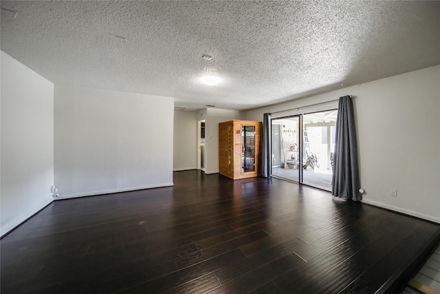 spare room with a textured ceiling and dark hardwood / wood-style floors