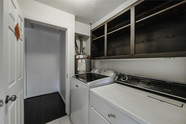 washroom with washer and dryer, a textured ceiling, and secured water heater