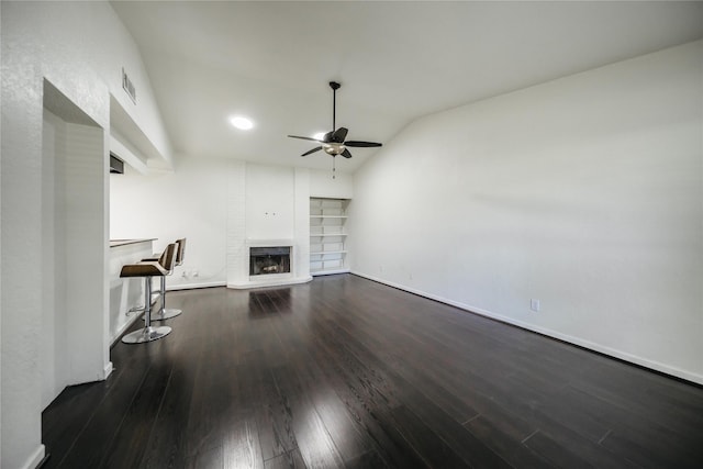 unfurnished living room featuring a brick fireplace, dark hardwood / wood-style flooring, lofted ceiling, and ceiling fan