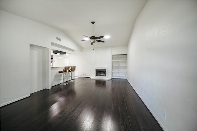 unfurnished living room with vaulted ceiling, ceiling fan, a fireplace, and dark hardwood / wood-style floors