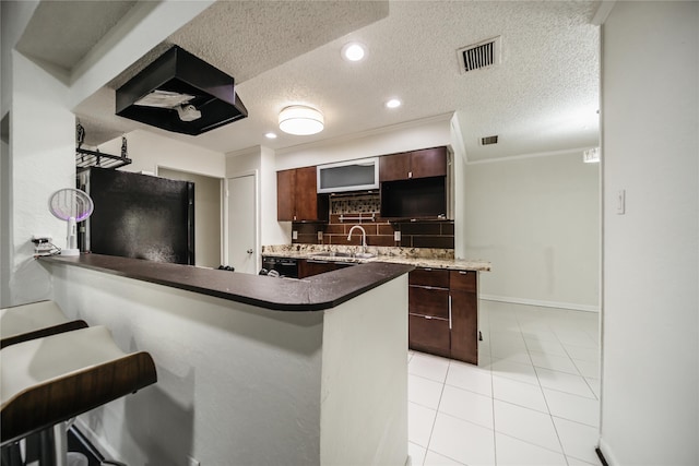 kitchen with a textured ceiling, black refrigerator, sink, kitchen peninsula, and dark brown cabinets