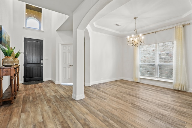 foyer entrance with light wood-type flooring, plenty of natural light, and a chandelier