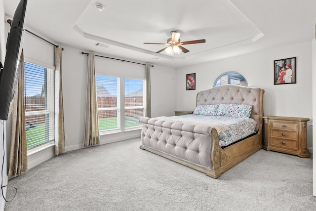 carpeted bedroom with a tray ceiling and ceiling fan